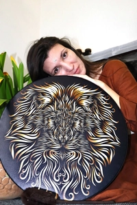 Artistic shamanic lion drum with golden mane design held by a woman in a lifestyle setting
