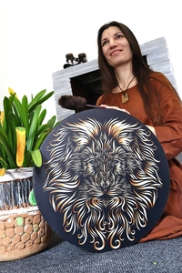 Detail of shamanic frame drum with golden lion print and plush mallet in hands
