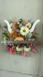 Detail of 40cm Highland Cow wreath with daisies, lavender, and multi-pattern ribbons