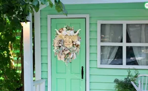 Detail of Scottish Highland Cow wreath with cream flowers and decorative ribbons on front door