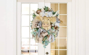Detail of Highland Cow wreath with white roses and plaid ribbons on a white door