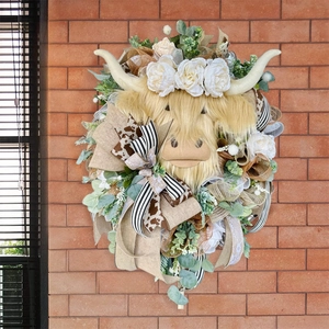 Rustic Highland Cow wreath with white roses and eucalyptus leaves on a brick wall