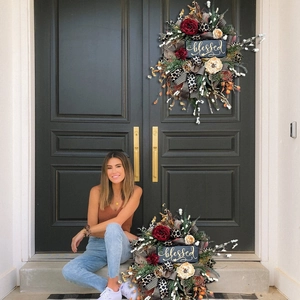 Detail of autumn wreath with peonies, ribbons, and a wooden 'blessed' sign on a door
