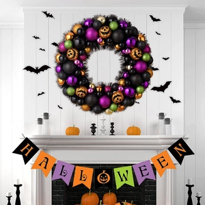 Dettaglio ghirlanda di Halloween con palline colorate e zucche sopra un camino bianco