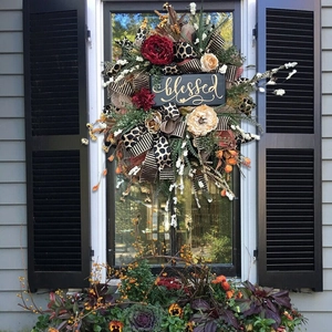 Detail of harvest wreath with floral accents, ribbons and a blessed wooden plaque
