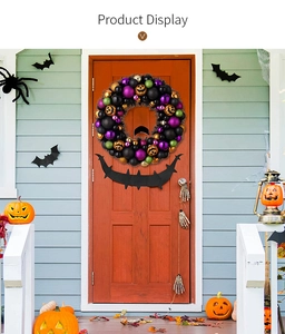 Ghirlanda di Halloween con decorazioni nere viola verdi e zucche su una porta arancione