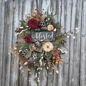 Autumn floral wreath with Blessed sign and leopard ribbons on gray wooden background