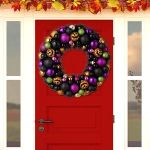 Dettaglio ghirlanda di Halloween con palline glitterate e zucche nere su una porta rossa