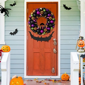 Ghirlanda di zucca di Halloween con ornamenti viola e verdi su una porta d'ingresso arancione