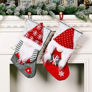 Detail of grey and red Christmas stockings with plush gnomes hanging on a white fireplace