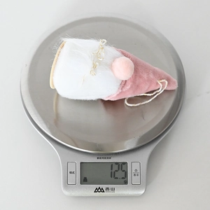 Detailansicht eines rosa Plüschzwergs auf einer Waage mit einem Gewicht von 12,5 g