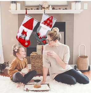 Detail of two Christmas gnome stockings in red and grey with snowflakes and 3D plush designs