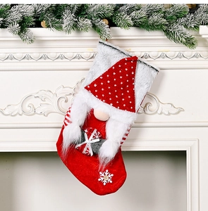 Detail of Christmas gnome stocking with knitted red hat hanging on white fireplace