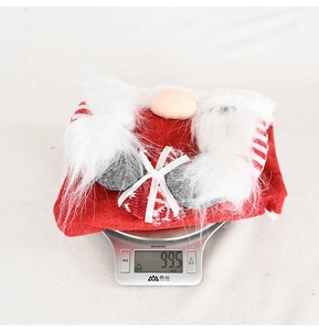 Detailed view of a plush Christmas gnome decoration being weighed on a white digital scale