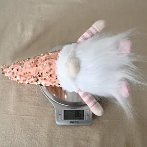 Weight measurement of a pink sequined Christmas gnome plush with striped legs on a scale