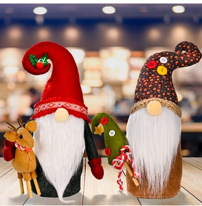 Close-up of handmade Christmas gnomes with reindeer and mini tree on wooden surface