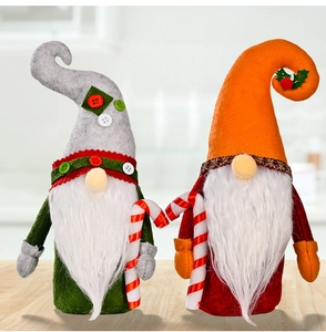 Close-up of plush Christmas gnomes with hooked hats and festive candy canes on wood