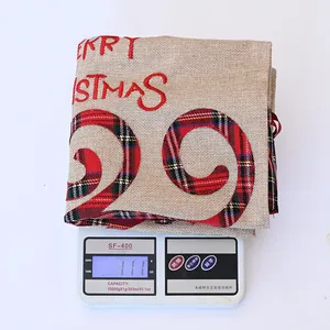 Detaillierte Gewichtsmessung eines karierten Merry Christmas Jutesacks auf einer Digitalwaage