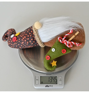 Close-up of a Christmas gnome doll on an electronic scale weighing 134.5 grams