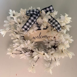 Artificial white dogwood wreath with black and white buffalo plaid bow and welcome sign