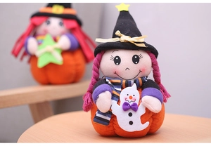 Detail of plush Halloween witch doll sitting on a pumpkin with mini ghost accessory