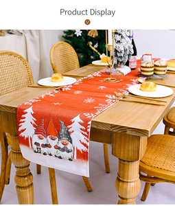 Close-up of red Christmas gnome table runner on wooden dining table with snowflakes