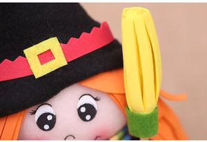 Close-up of Halloween witch doll featuring a black felt hat and orange hair decoration