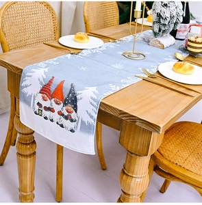 Close-up of a blue Christmas table runner with gnomes and snowflakes on a wooden table