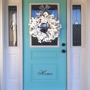 Artificial white dogwood wreath with buffalo plaid bow on front door decor