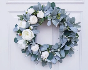 Detail of faux white peonies and velvet lamb's ear leaves on a decorative door wreath