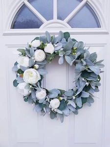 Detail of faux white roses and dusty miller foliage on a rustic wooden door wreath