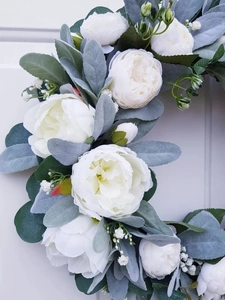Detailed close-up of handmade white silk peonies and flocked silver leaf on a wood door