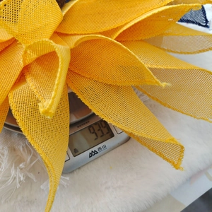 Close-up of yellow sunflower wreath material on a digital scale weighing 93.9 grams