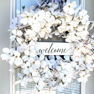Elegant white dogwood floral wreath featuring buffalo check bow and welcome sign for front door
