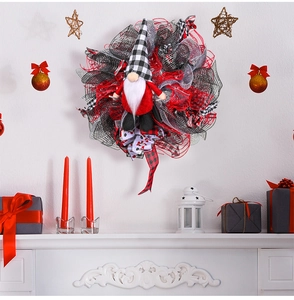 Detail van een kerstkrans met gnome en rood-zwarte linten opgehangen boven de open haard