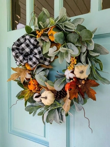 Detail von Herbst-Kürbiskranz mit Baumwolle, Zapfen und schwarz-weiß karierter Schleife