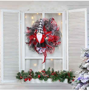 Detailweergave van kerstgnomkrans met rood en zwart gaaslint op een vintage venster