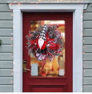 Detailweergave van een kerstgnome krans met rood-zwart gaas en gedecoreerde linten