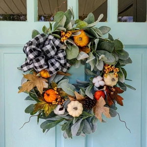 Herbstkranz mit Eukalyptus Kürbissen und karierter Schleife an blauer Haustür