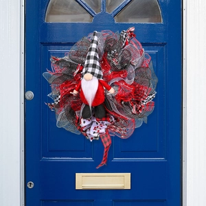 Kerstkrans met kabouter en rood-zwarte linten aan een donkerblauwe houten deur