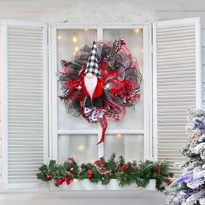 Kerstkrans met kabouter en rood-zwarte mesh linten op een rustieke witte raamachtergrond