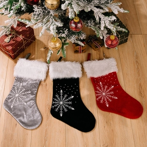 Three large Christmas stockings with snowflakes and white faux fur trim on wood floor