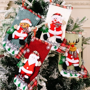 Detail of four linen Christmas stockings with 3D characters hanging on a tree
