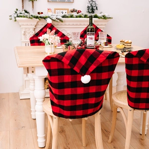 Red and black buffalo plaid Christmas chair covers with white plush pom poms for dining decor