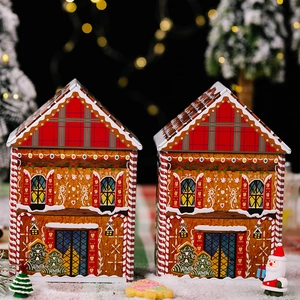 Detailed view of gingerbread house-shaped tin gift boxes with festive Christmas motifs