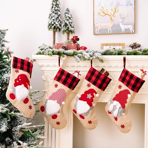 Set of four burlap Christmas stockings with gnome designs hanging on a festive fireplace