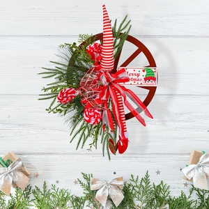 Christmas wagon wheel wreath with elf legs and green pine needles on white wood wall