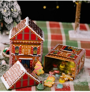 Gingerbread house-shaped tin box filled with colorful candies and festive cookies