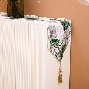 Ink floral table runner with elegant tassels on a minimalist white cabinet top