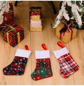 Close-up of three plaid Christmas mini stockings with snowflake patterns on wood background